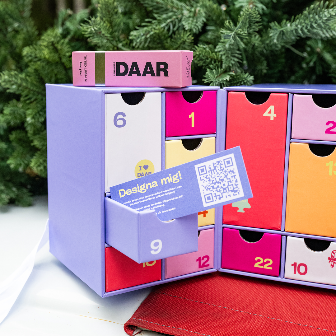Öppen julkalender med ett kort märkt Designa mig och en QR-kod.